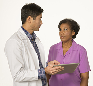 Médico y paciente hablando. El médico sostiene una tableta.